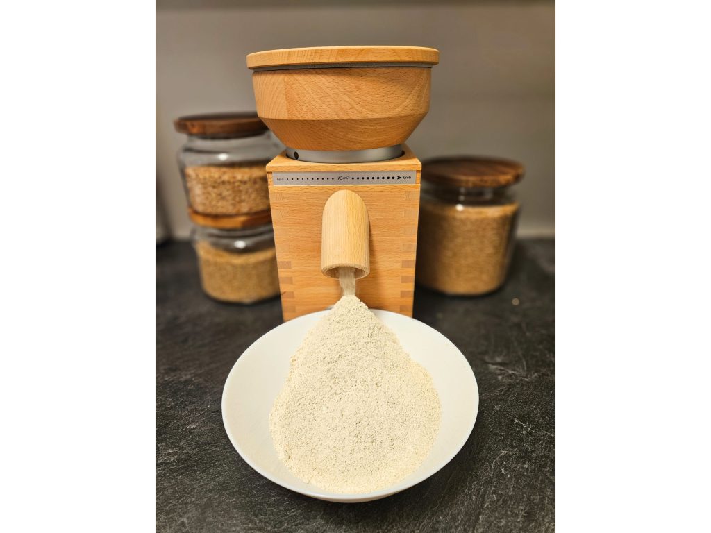komo mill grinding einkorn wheat berries on a grey counter