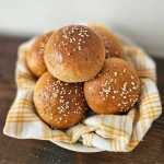 fresh milled hamburger buns in a bowl with a striped towel