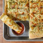cheesy sourdough breadsticks cut up in a baking tray