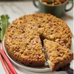 Rhubarb Sourdough Coffee Cake on a plate with fresh rhubarb on the side