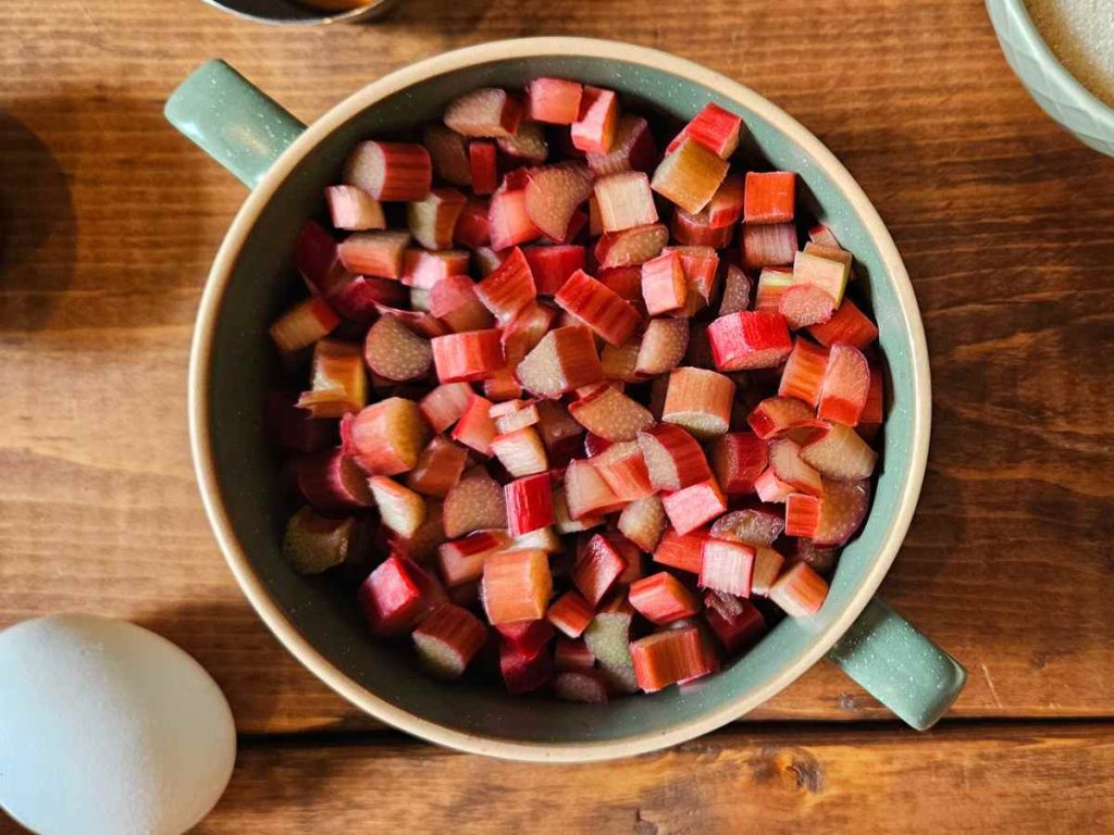 chopped rhubarb in a turquoise bowl on a wooden counter